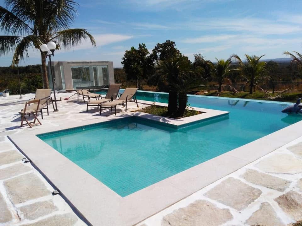 Piscina ampla com prainha, ilha central e palmeiras