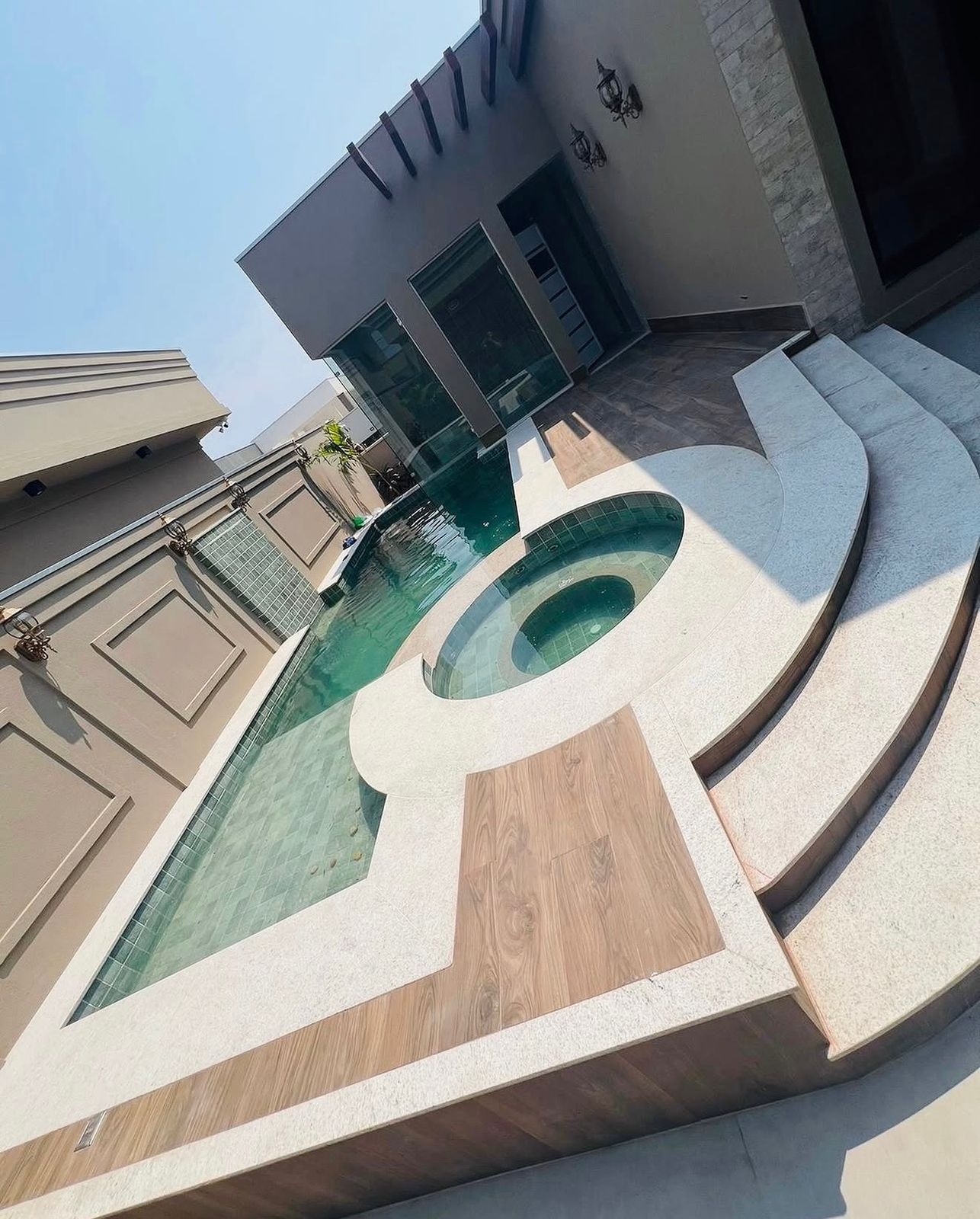 Piscina residencial com spa circular e escada curva